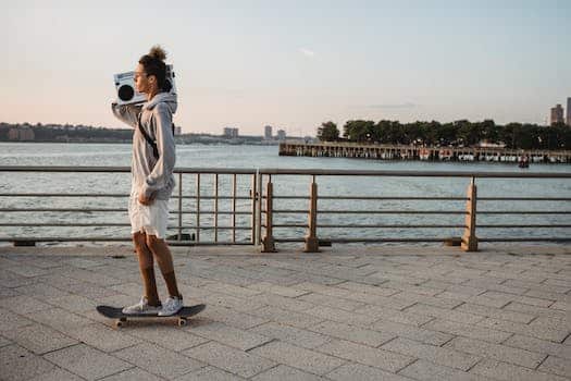 Cheerful young man with boombox riding skateboard