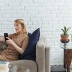 Elderly woman chatting on smartphone on sofa in living room