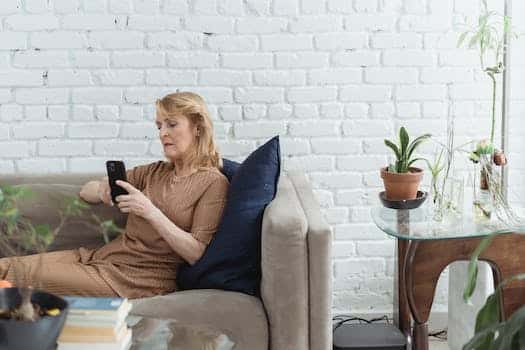 Elderly woman chatting on smartphone on sofa in living room