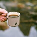 Man Holding a Small Pot with an Instant Soup by a Pond