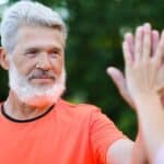 Pensive aged man giving high five to friend