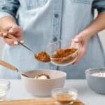 Person Adding a Spoon of Cinnamon in a Bowl