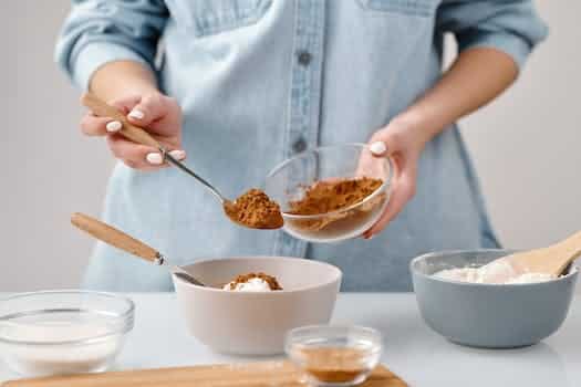 Person Adding a Spoon of Cinnamon in a Bowl