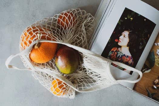 Top view of opened recipe book at table together with handbag with assorted fruits inside