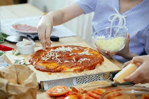 Woman sprinkling cheese on pizza