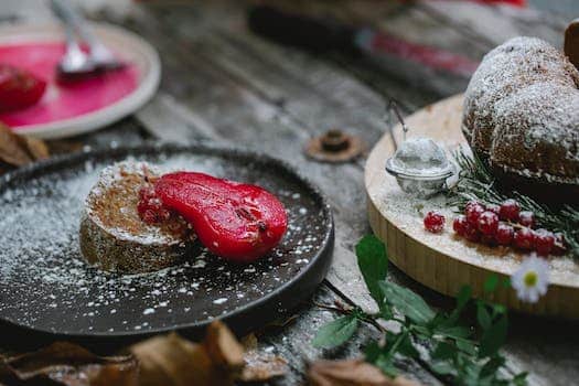 Appetizing composition of freshly baked sweet pie served on black plate with red marinated pear and decorated with sugar powder