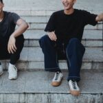 Crop cheerful Asian male friends resting on street steps