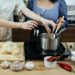 Crop faceless women cooking traditional noodle dish together