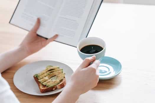 Crop person with cup of americano and book