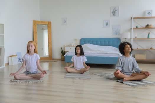 Full body of concentrated multiethnic girls in casual clothing meditating in bright room with eyes closed and arms folded on crossed legs