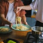 Man Putting Cooked Spaghetti Pasta on a Plate