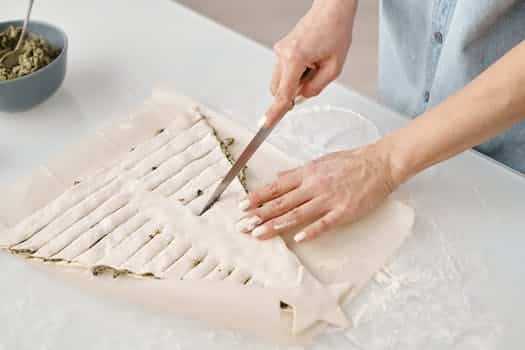 Person Slicing a Christmas Tree Shaped Bread With Fillings