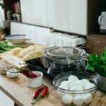 Table with spices chopping board with noodles and bowls in kitchen