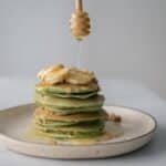 Tasty pancakes with fresh bananas served on plate and table on white blurred background