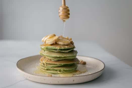 Tasty pancakes with fresh bananas served on plate and table on white blurred background