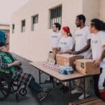 Volunteers Assisting an Old Man on a Wheelchair