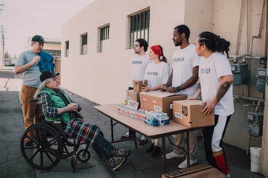 Volunteers Assisting an Old Man on a Wheelchair