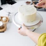 Woman hands decorating biscuit cake with cream