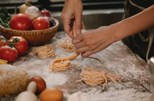 Crop anonymous female chef making homemade Italian pasta nests while cooking in modern kitchen