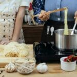 Crop women cooking pasta together