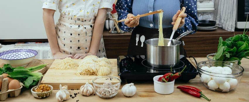 Crop women cooking pasta together