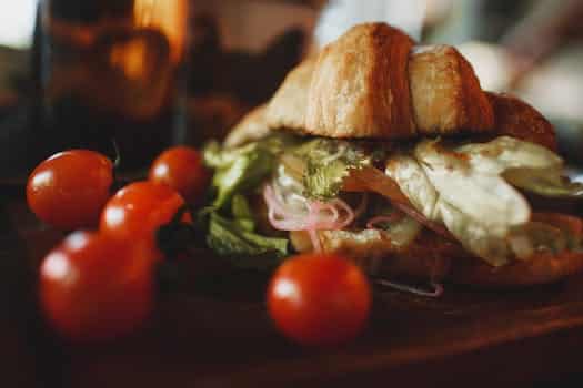 Crunchy veggie croissant sandwich served on board with tomatoes