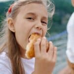 Happy little girl eating tasty croissant