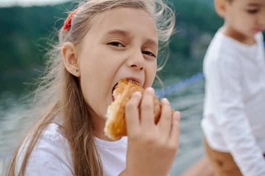 Happy little girl eating tasty croissant