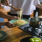 Man Putting Cooked Spaghetti Pasta on a Plate