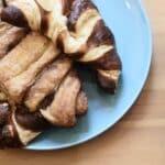 Top view of delicious crusty croissants with chocolate topping on wooden table in bakery