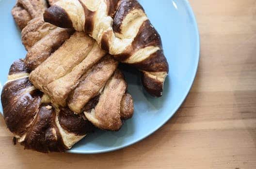 Top view of delicious crusty croissants with chocolate topping on wooden table in bakery