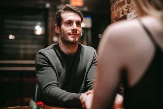 Young man in casual clothes sitting at table in modern cafe with girlfriend