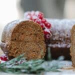 Appetizing homemade chocolate sponge cake with berries and rosemary sprig placed on table against blurred background