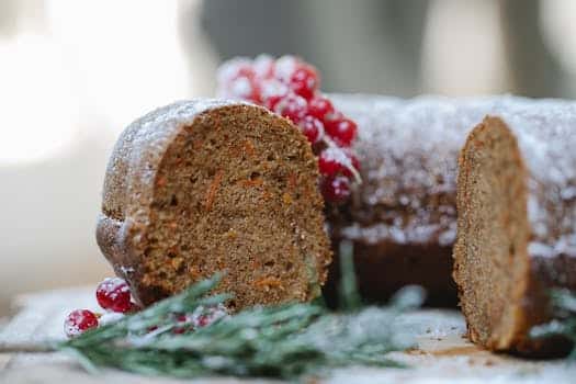 Appetizing homemade chocolate sponge cake with berries and rosemary sprig placed on table against blurred background