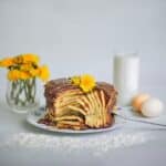 Composition of yummy homemade pancakes topped with chocolate cream placed on white table near glass of fresh milk and glass with yellow flowers