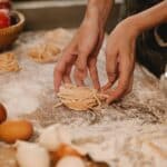 Crop unrecognizable housewife making pasta nests on table