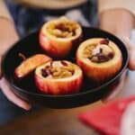 Faceless woman with delicious baked apples in house