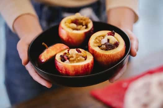 Faceless woman with delicious baked apples in house