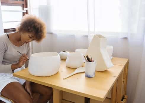 Focused young artist painting ceramic bowl