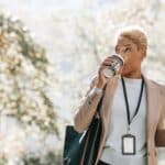 Young African American businesswoman drinking takeaway beverage during coffee break in park