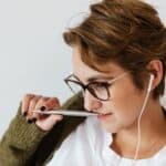 Content woman with earphones and stylish pen