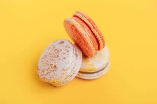 From above of delicious little homemade macaroons placed on bright yellow background of studio