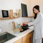 Asian woman cooking near stove