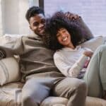 Beloved African American couple cuddling and smiling on couch