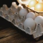 Carton box with fresh eggs placed on wooden surface