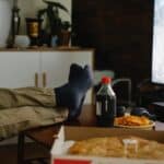 Crop person with crossed legs on table against monitor