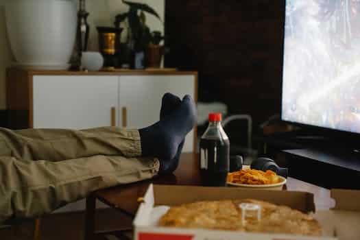 Crop person with crossed legs on table against monitor