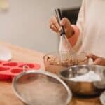 Crop woman mixing batter in kitchen