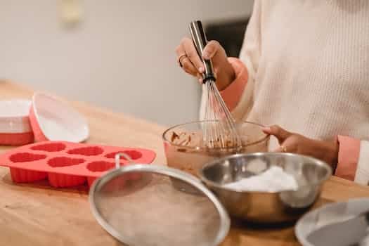 Crop woman mixing batter in kitchen