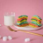 Delicious bright pancake served on plate near fork and white marshmallow on pink background